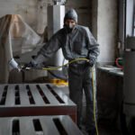 front-view-man-spraying-powder-paint-from-gun